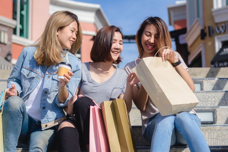 Friends sitting on steps with shopping bags